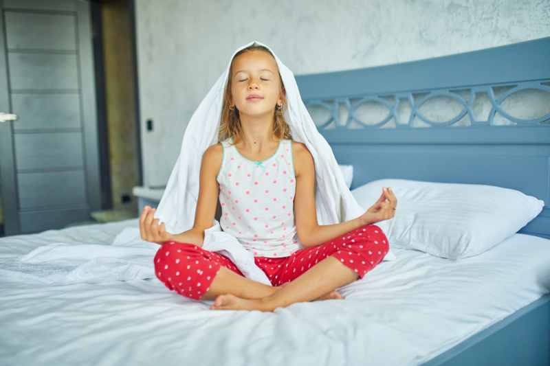 child girl in pajamas sitting on a bed in lotus po 2022 01 19 00 21 41 utc 1